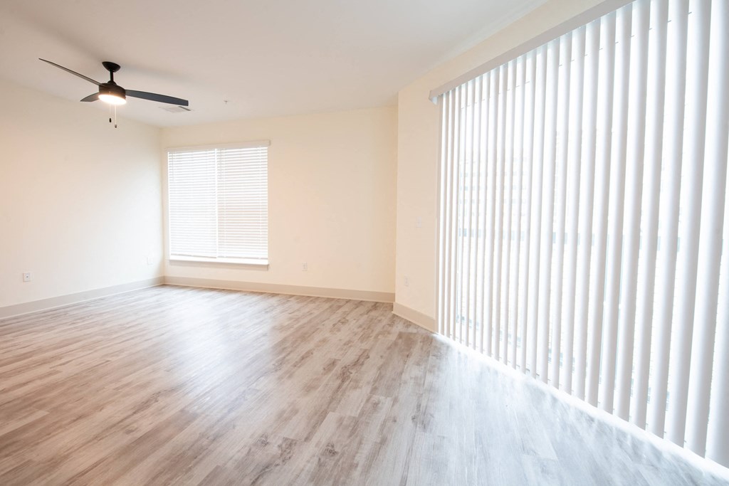 an empty living room with a large window and wood floors