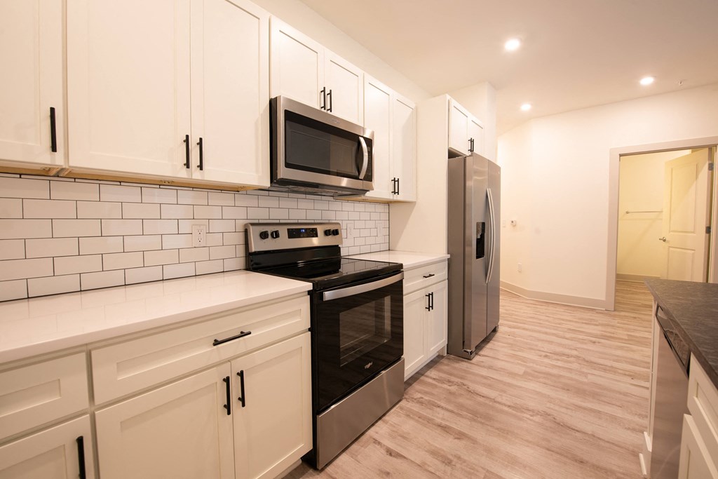 a kitchen with white cabinets and black appliances and a stainless steel refrigerator
