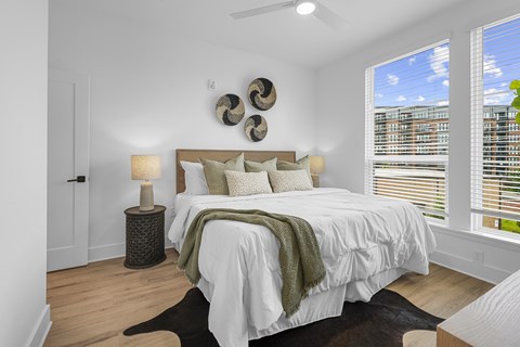 A bedroom with a large bed and a window with blinds.