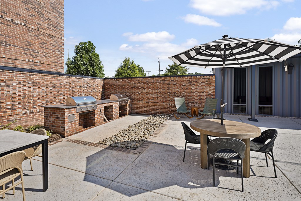 A patio with a table and chairs and an umbrella.