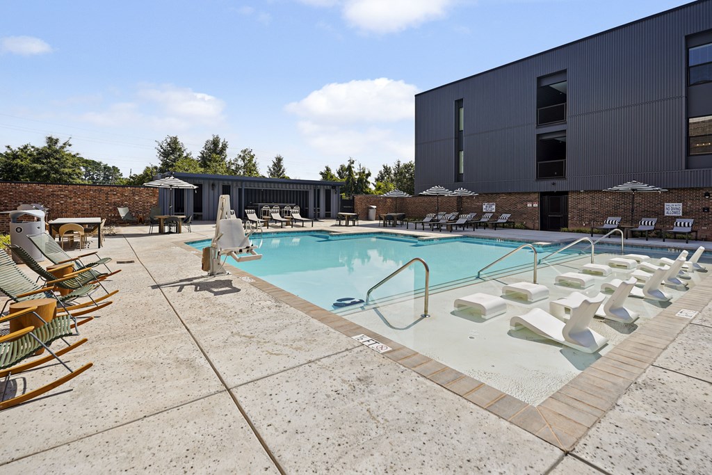 A pool with sun loungers and a building in the background.