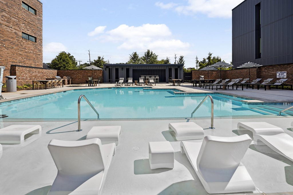 A pool with white chairs around it.