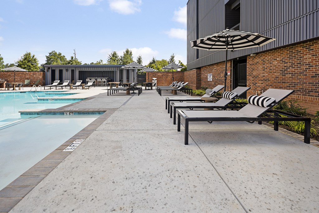 A pool with a concrete floor and a building in the background.