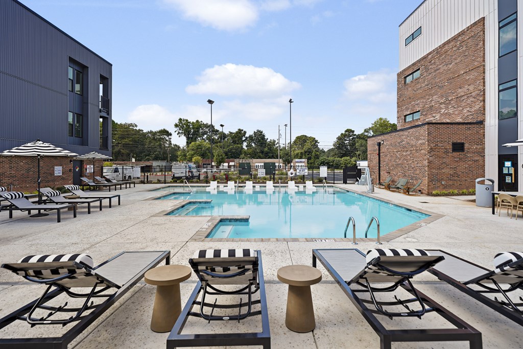 A pool surrounded by sun loungers and a building in the background.