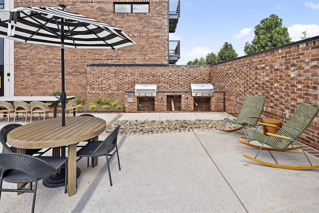 A patio with a table, chairs, and an umbrella.