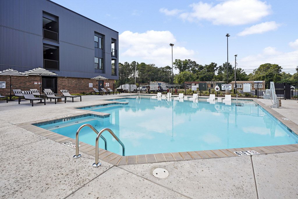 A large outdoor swimming pool with a metal ladder and steps leading into the water.