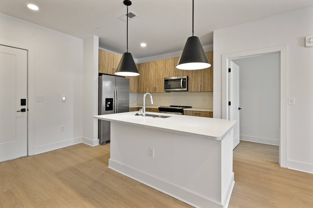 A modern kitchen with a white island and pendant lights.