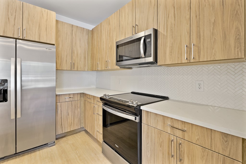 A kitchen with wooden cabinets and a stainless steel refrigerator.