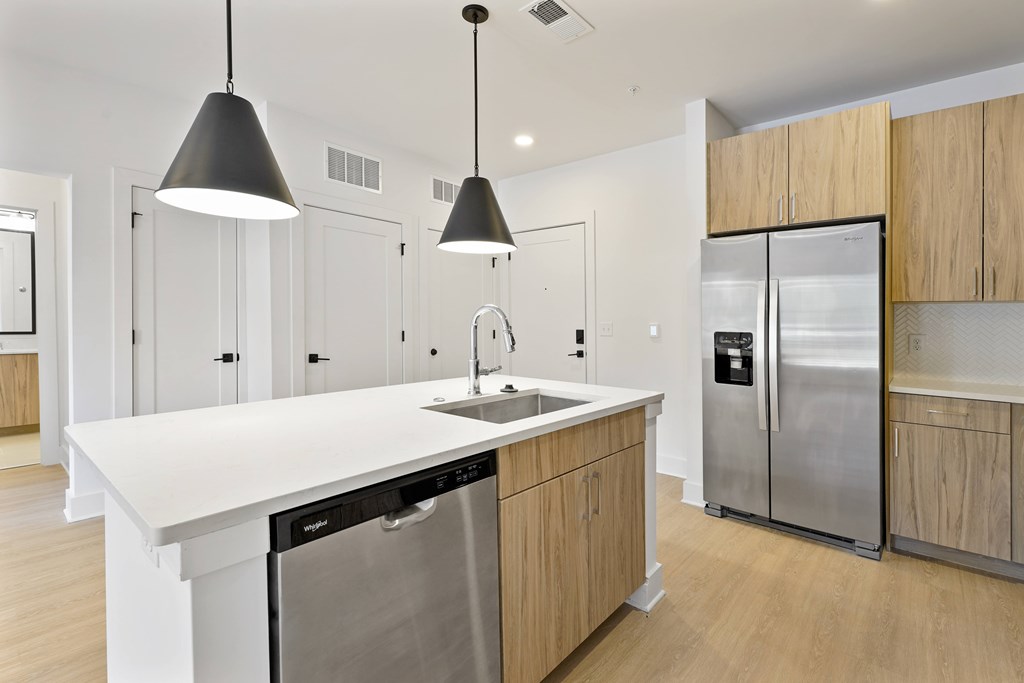 A modern kitchen with a white countertop and stainless steel appliances.