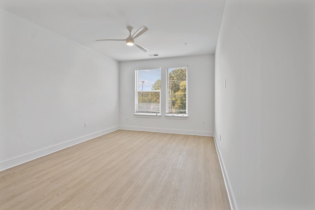 A room with a ceiling fan and a window with blinds.