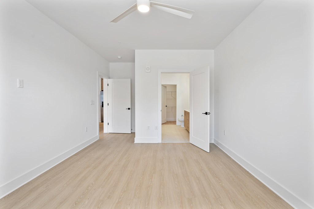 A long hallway with a fan and doors on both sides.