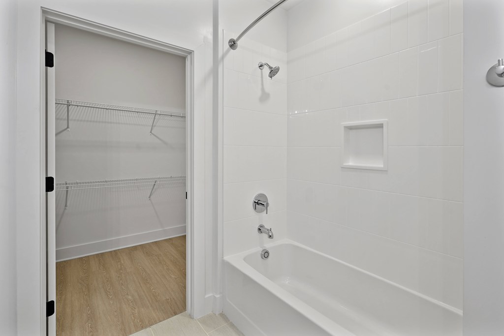 A white bathroom with a walk in shower and a white door.