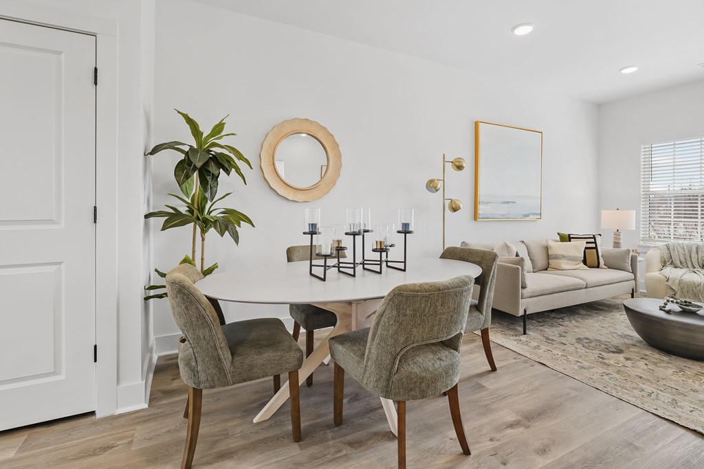 A modern dining room with a round mirror and a plant.
