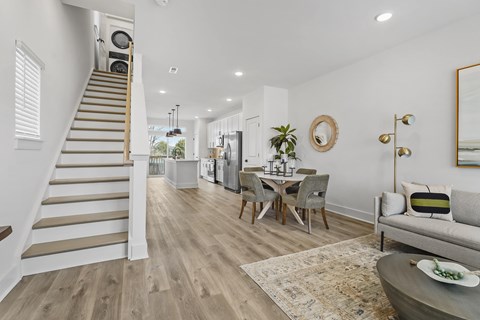 A living room with a grey couch and a dining table with chairs.