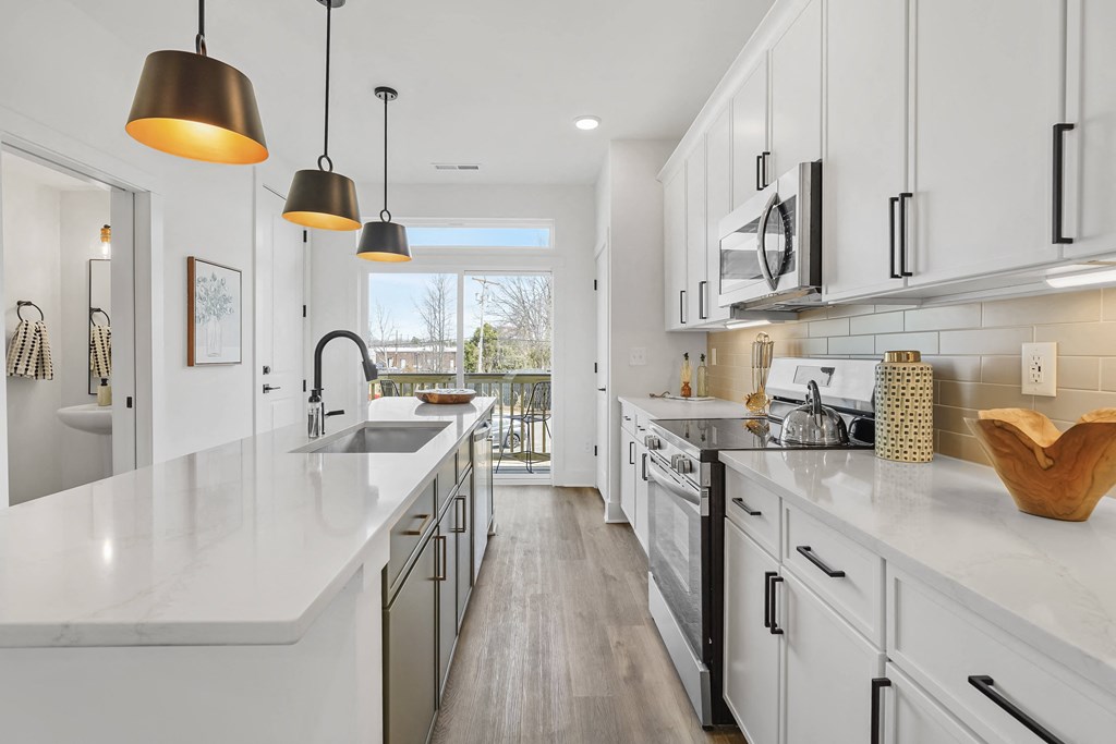 A modern kitchen with white cabinets and a marble countertop.