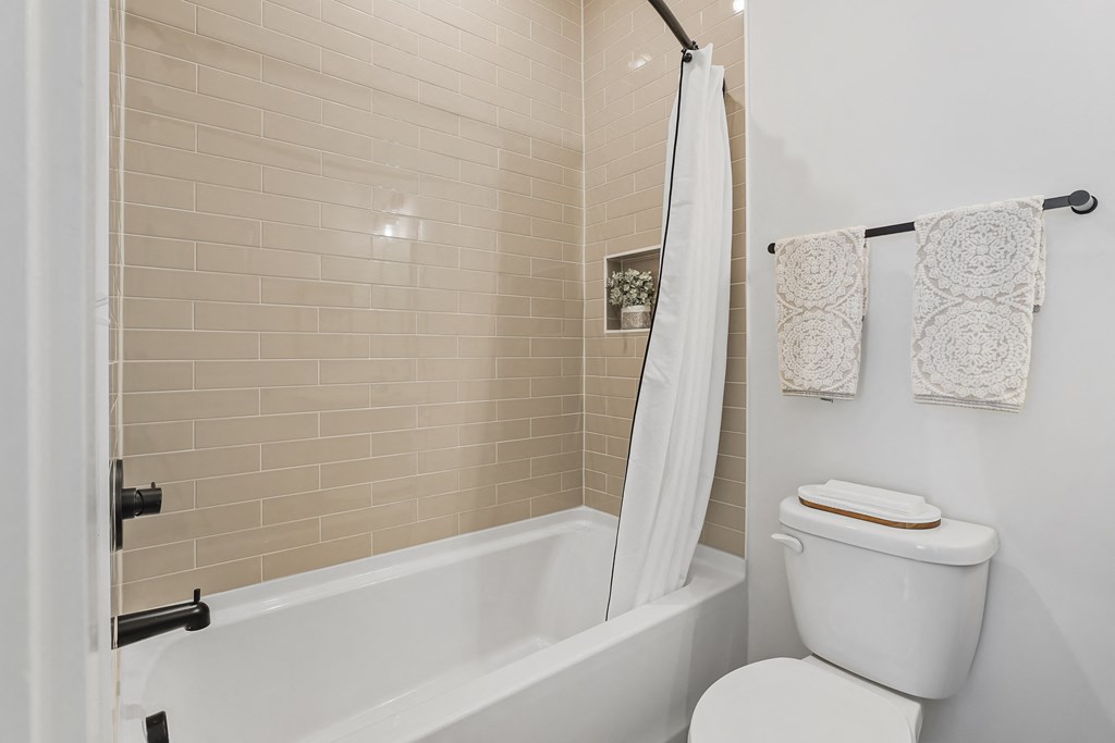 A white toilet sits next to a bathtub in a bathroom.