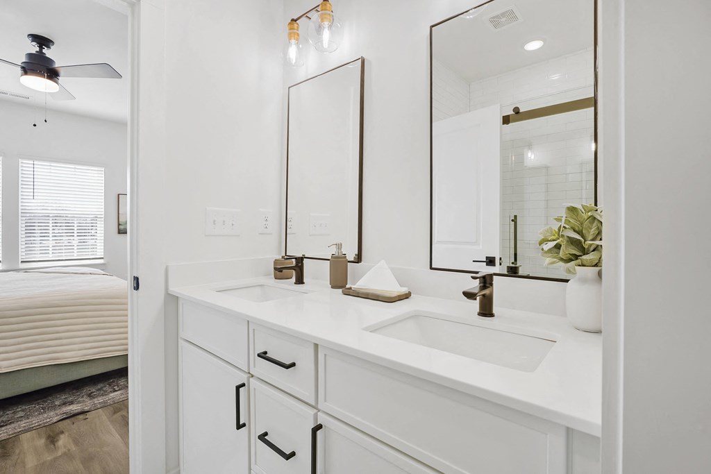 A white bathroom with a vanity, mirror, and a fan.