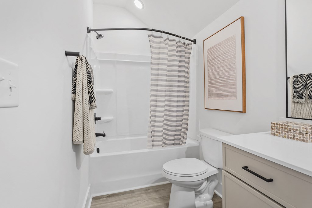 A white bathroom with a toilet, sink, and shower.