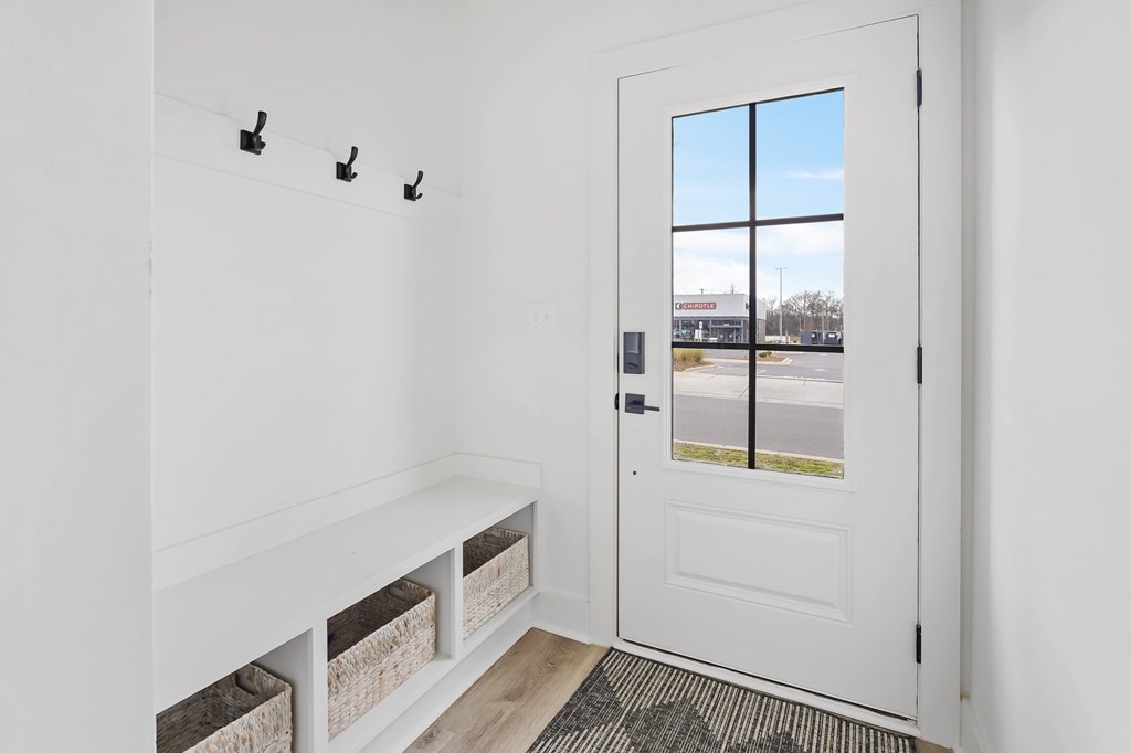 A white door with a window and a bench with storage baskets underneath it.