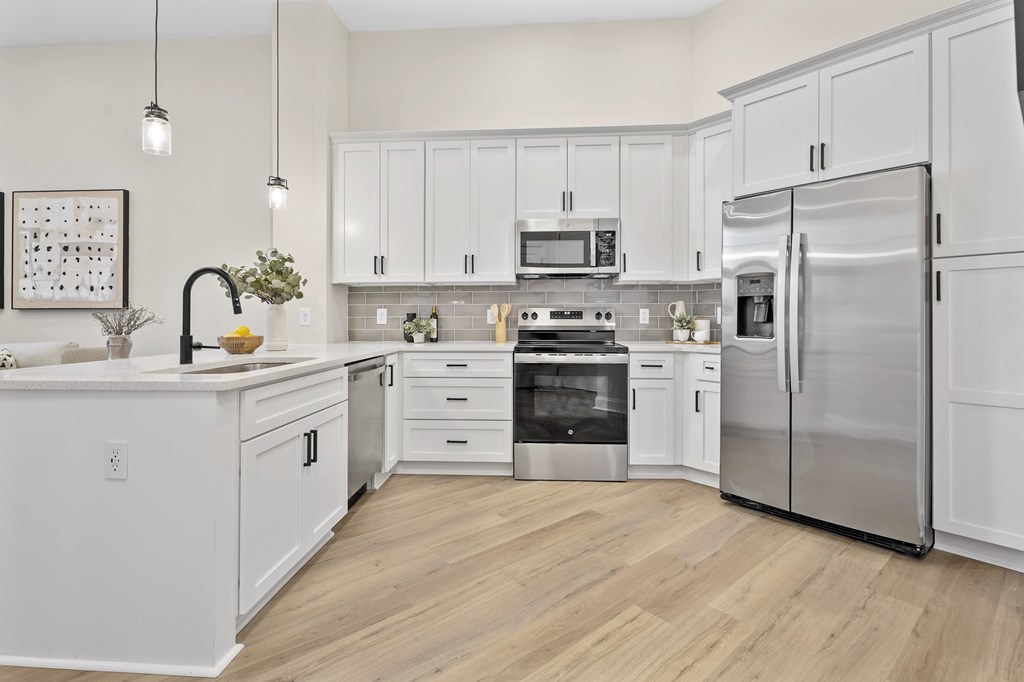 A modern kitchen with white cabinets and stainless steel appliances.