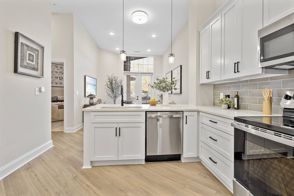 A modern kitchen with white cabinets and a wooden floor.