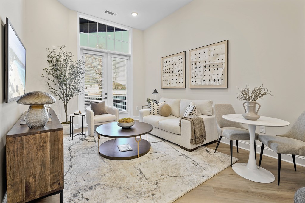 A living room with a white couch, a coffee table, and a TV on the wall.