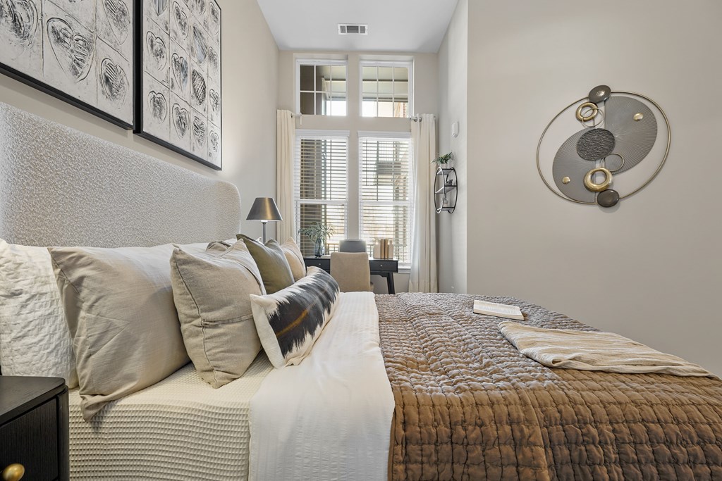 A bedroom with a bed, pillows, and a wall art.