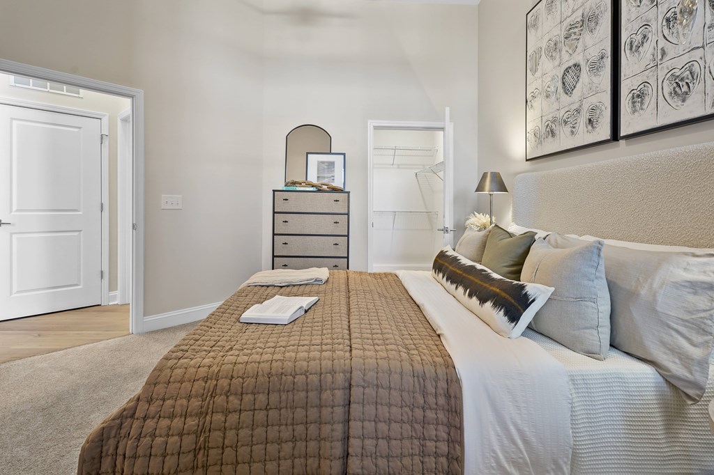 A bedroom with a bed, nightstand, and a dresser with a mirror.