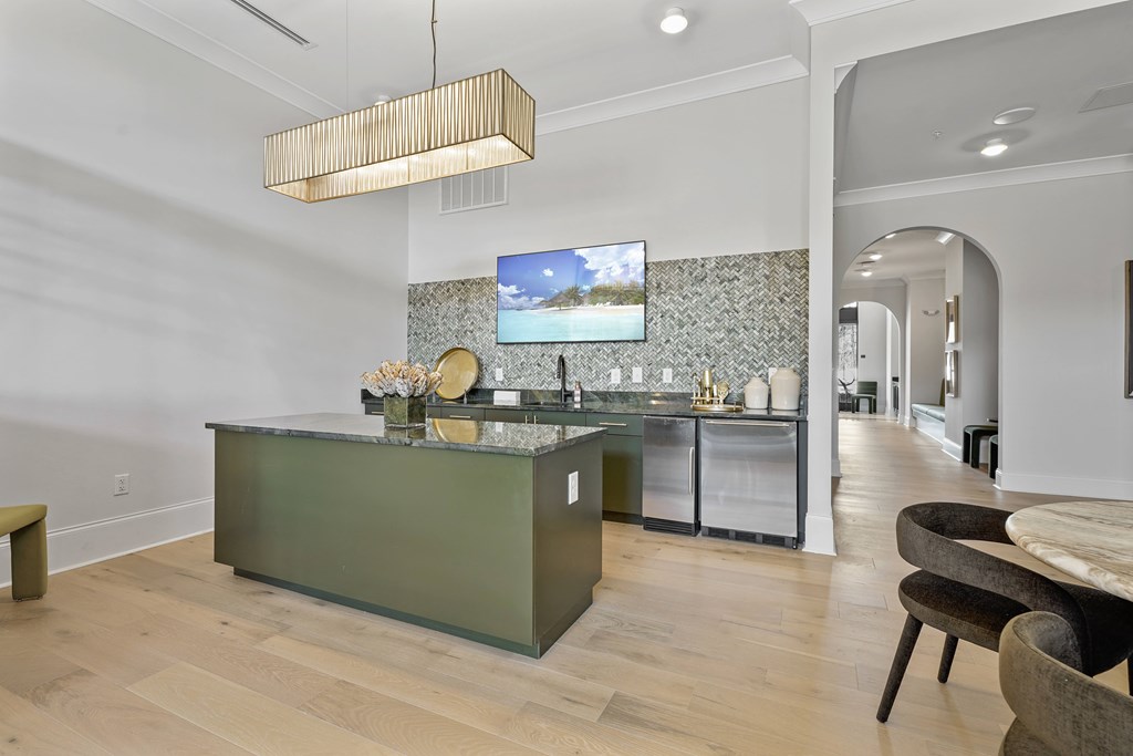 A modern kitchen with a green island and a television mounted on the wall.