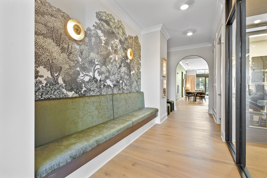 A long hallway with a green bench and a wall with a mural of trees.