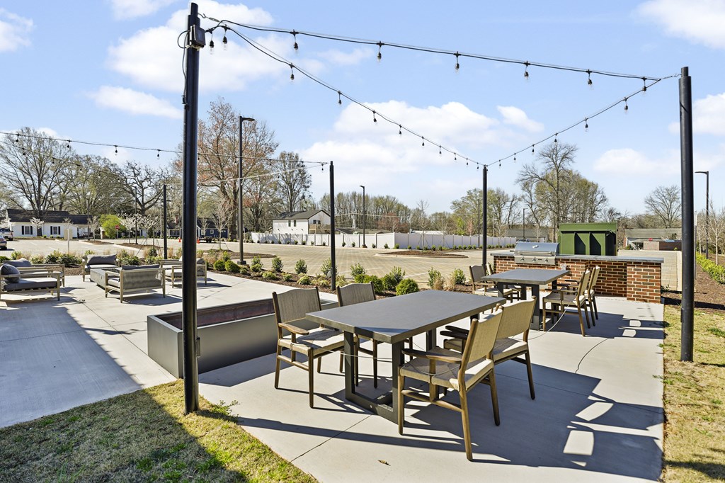 A patio with a table and chairs under string lights.