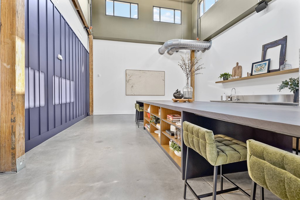 A kitchen with a long counter and green chairs.