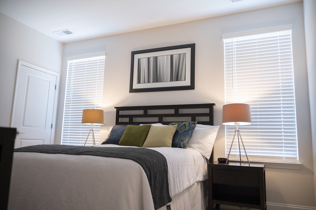 a bedroom with white walls and a large bed with white and green pillows at Landon Green Artisan Cottages Apartments, Hickory
