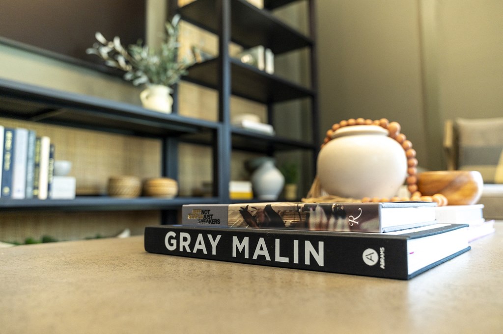 a stack of books on a table in front of a bookshelf at Landon Green Artisan Cottages Apartments, Hickory