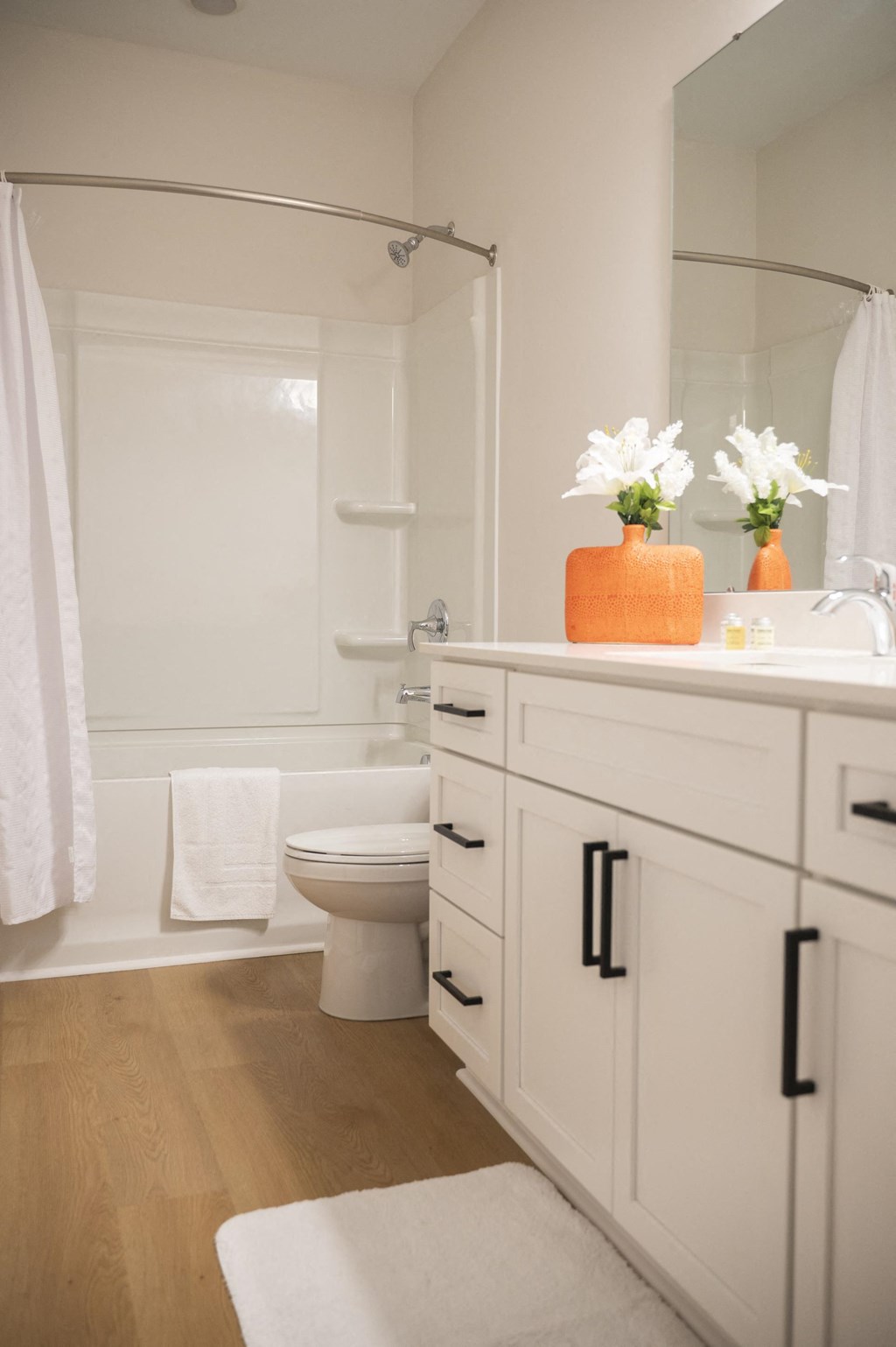 a bathroom with white cabinetry and a white toilet next to a white bathtub at Landon Green Artisan Cottages Apartments, Hickory, NC