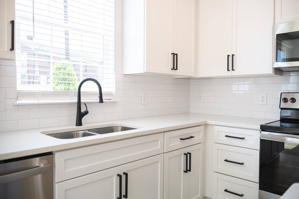 a kitchen with white cabinets and a large window at Landon Green Artisan Cottages Apartments, Hickory, 28601