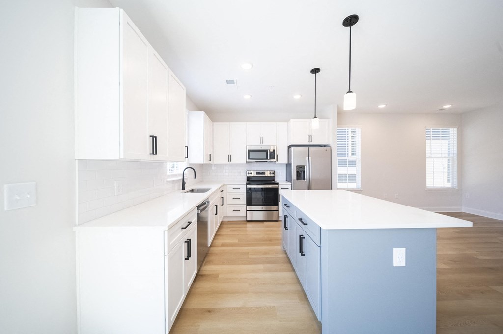a kitchen with cabinets and a blue island at Landon Green Artisan Cottages Apartments, Hickory, NC