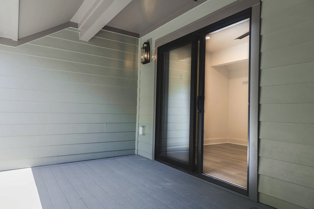 a glass door opens to a hallway with a wood floor and white walls