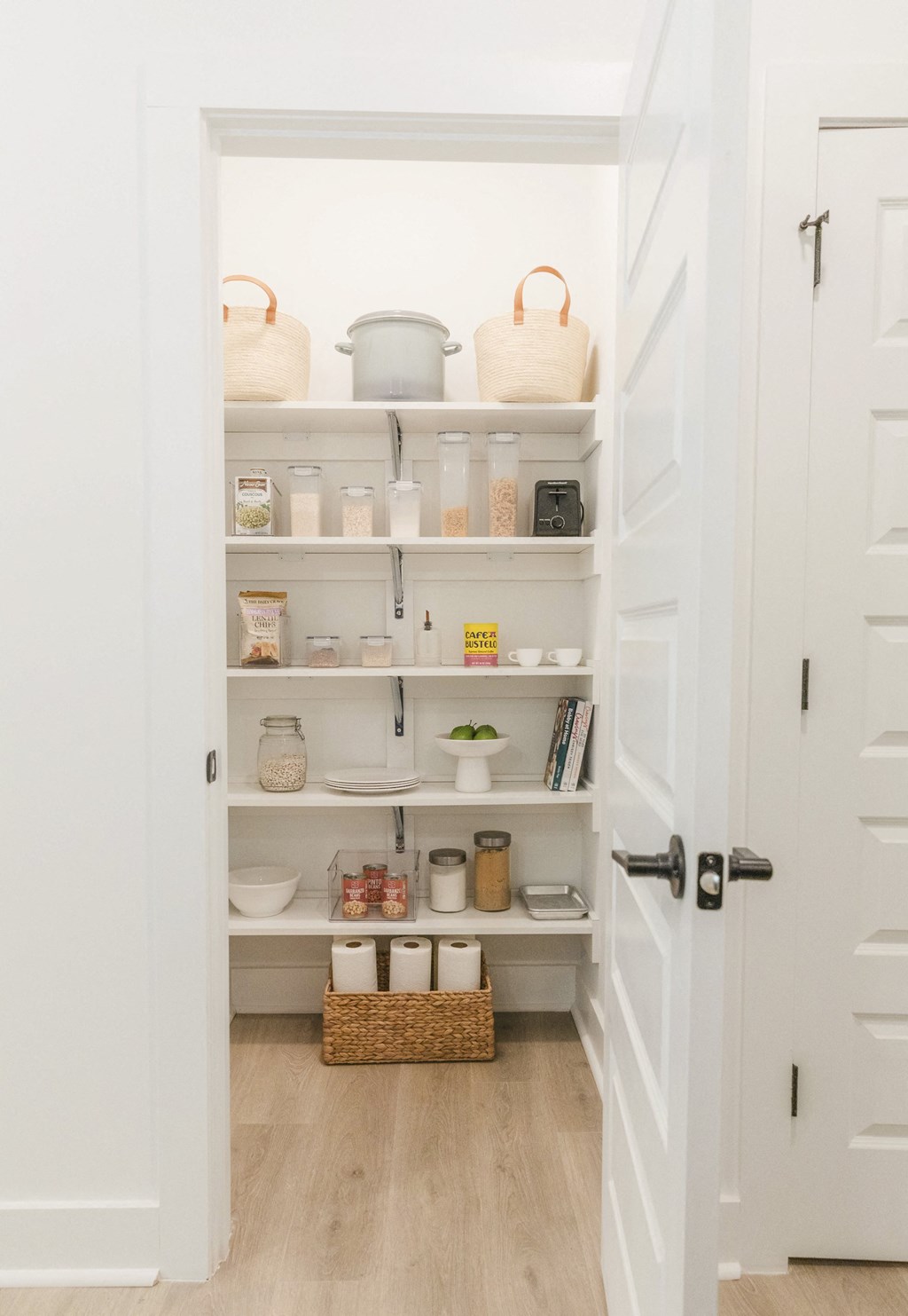 the pantry is organized with baskets and containers on the shelves