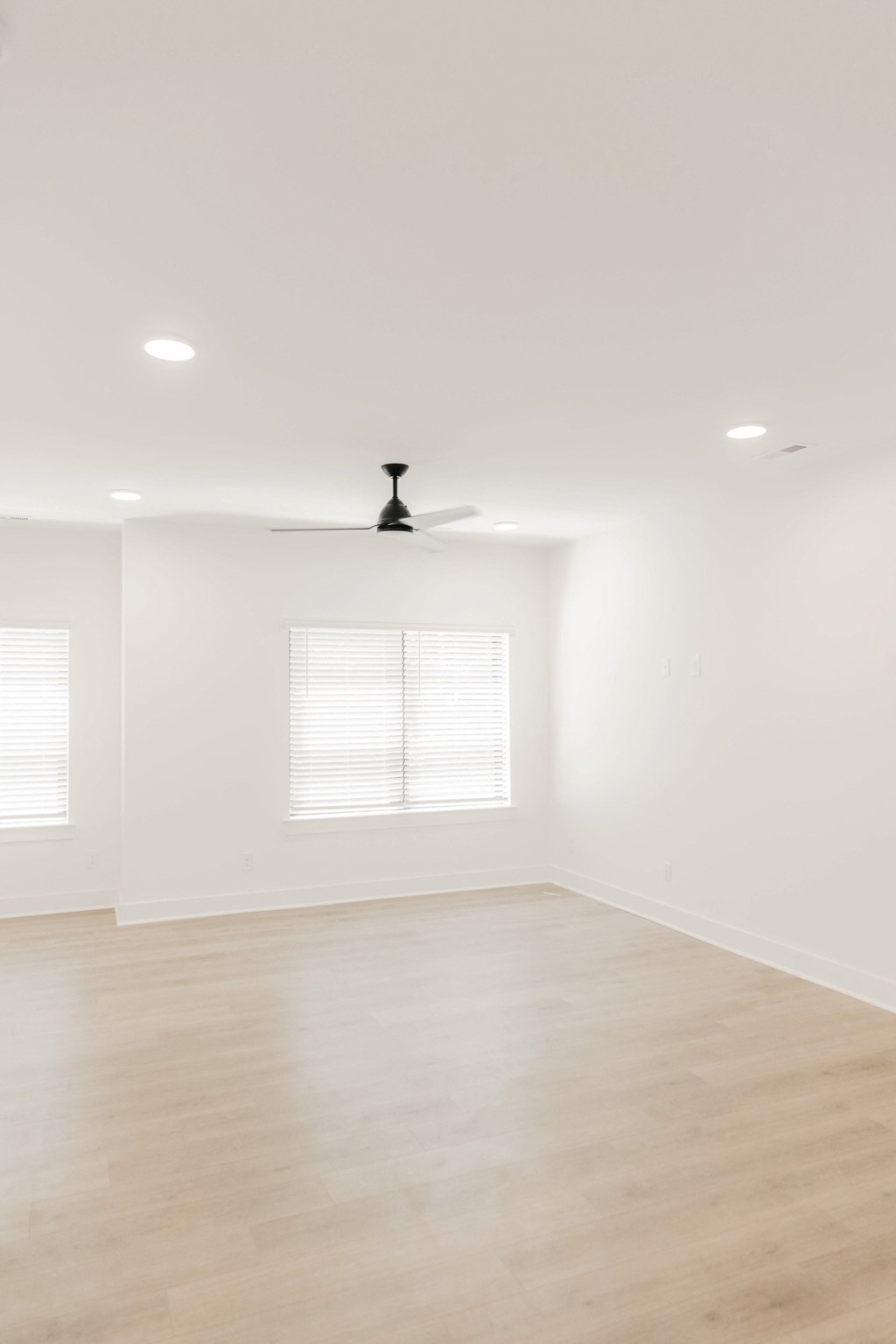 an empty living room with white walls and a ceiling fan
