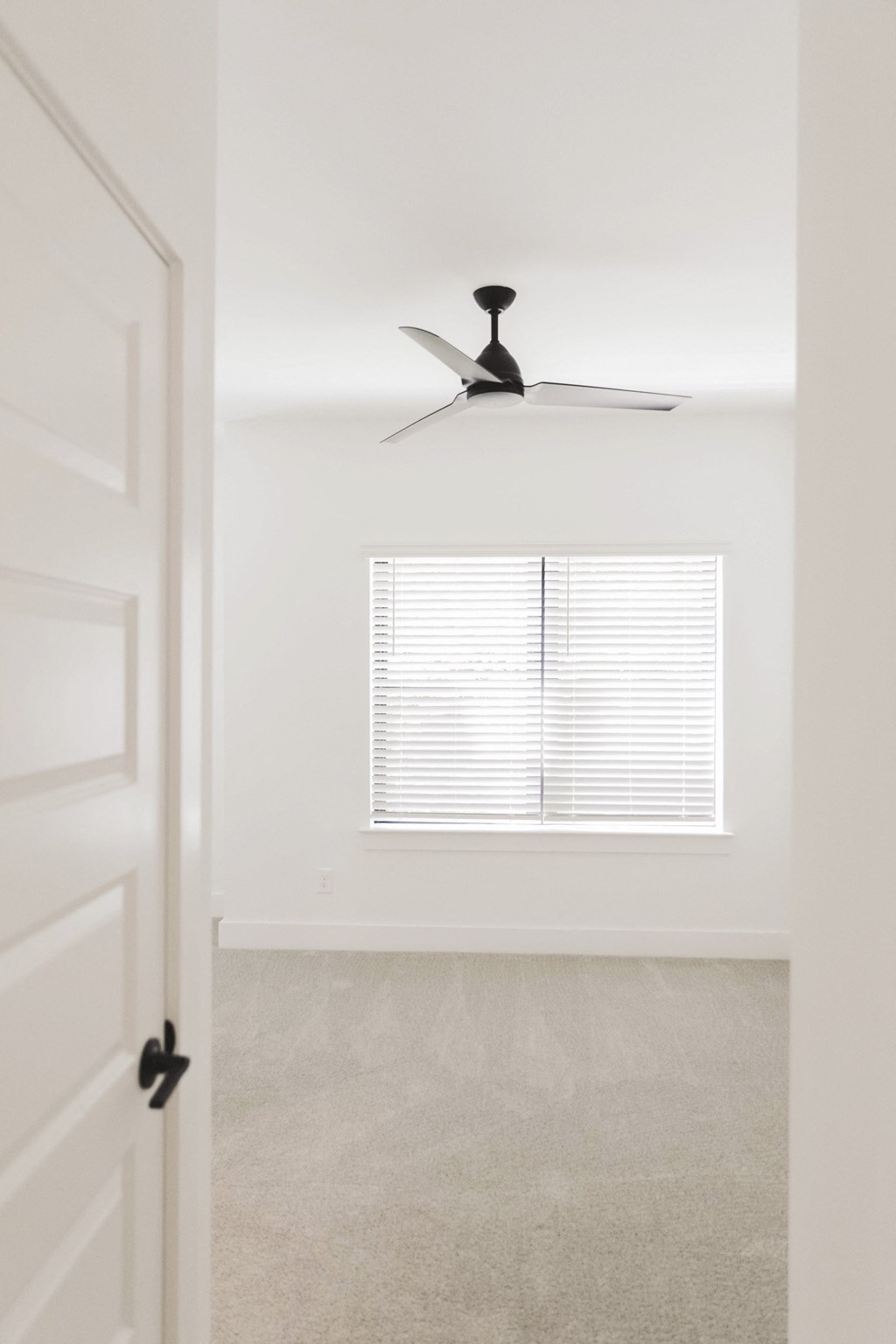 an empty room with a ceiling fan and a window