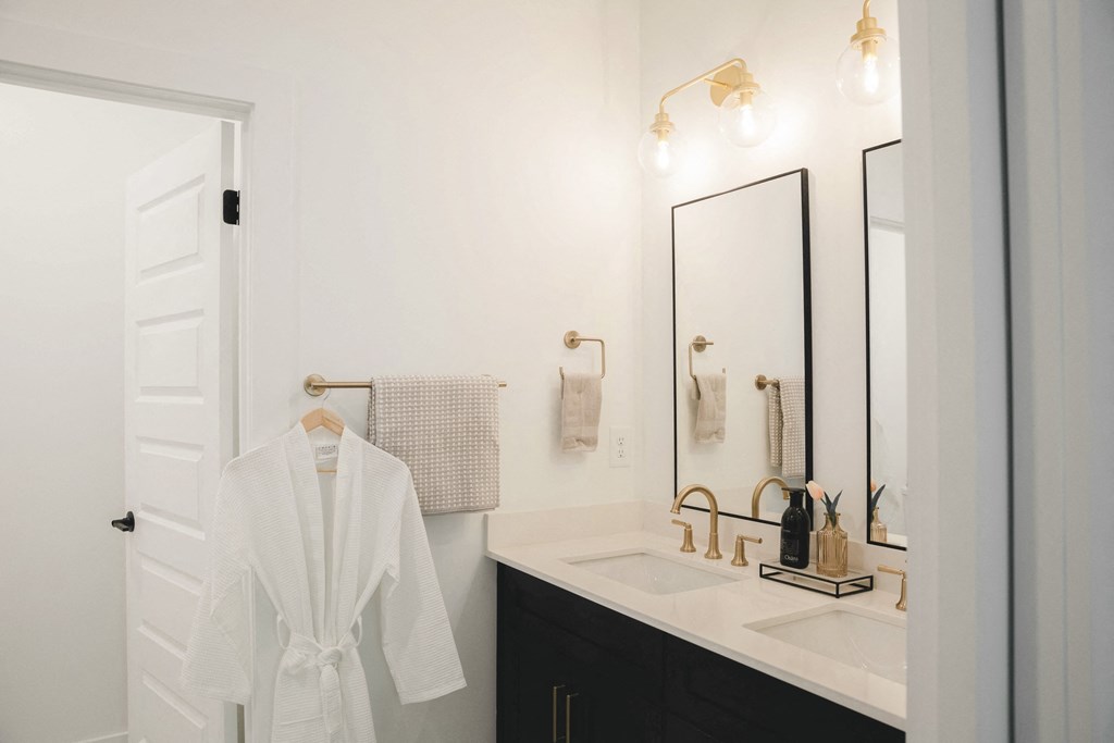 a bathroom with a white robe and a sink and a mirror