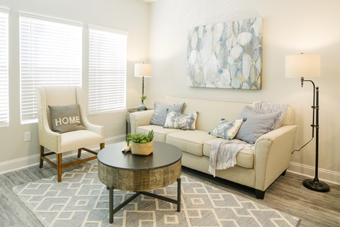 A living room with a white couch, a wooden chair with the word HOME on it, and a coffee table.