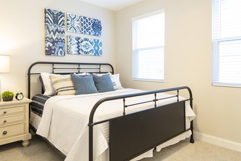 A bedroom with a black metal bed frame and a white bedspread.