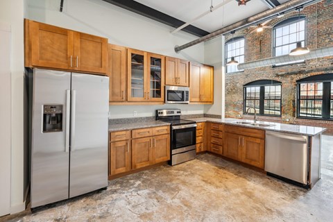 A kitchen with wooden cabinets and a brick wall.