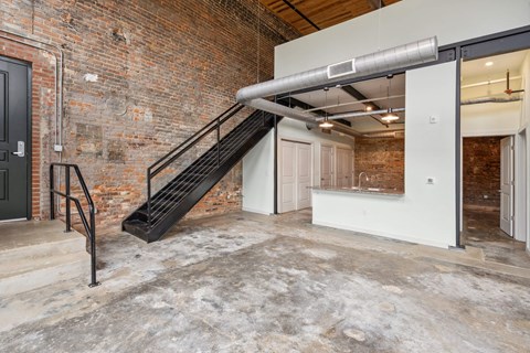 the lobby of a building with a staircase and a brick wall