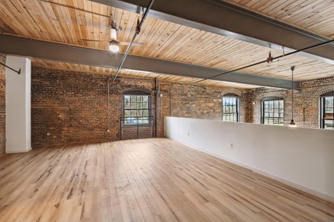 an empty room with exposed brick and wood floors and a white wall