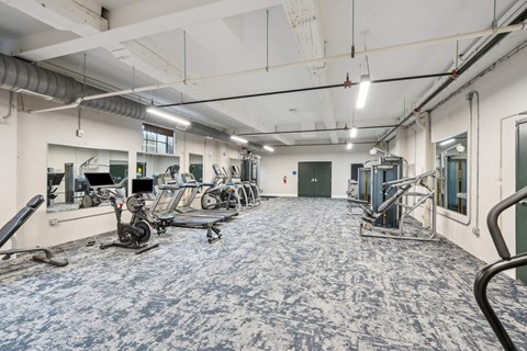 A gym with exercise equipment and a blue floor.