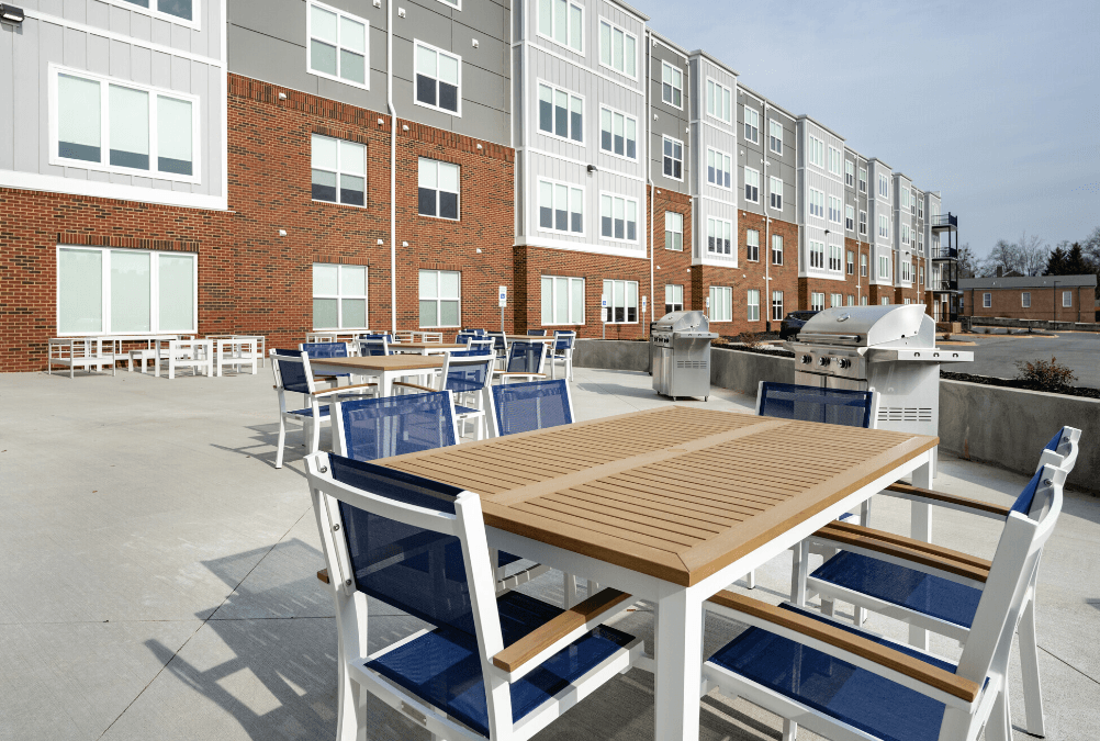a patio with tables and chairs and a grill in front of an apartment building at Park View Greer, Greer, SC, 29365
