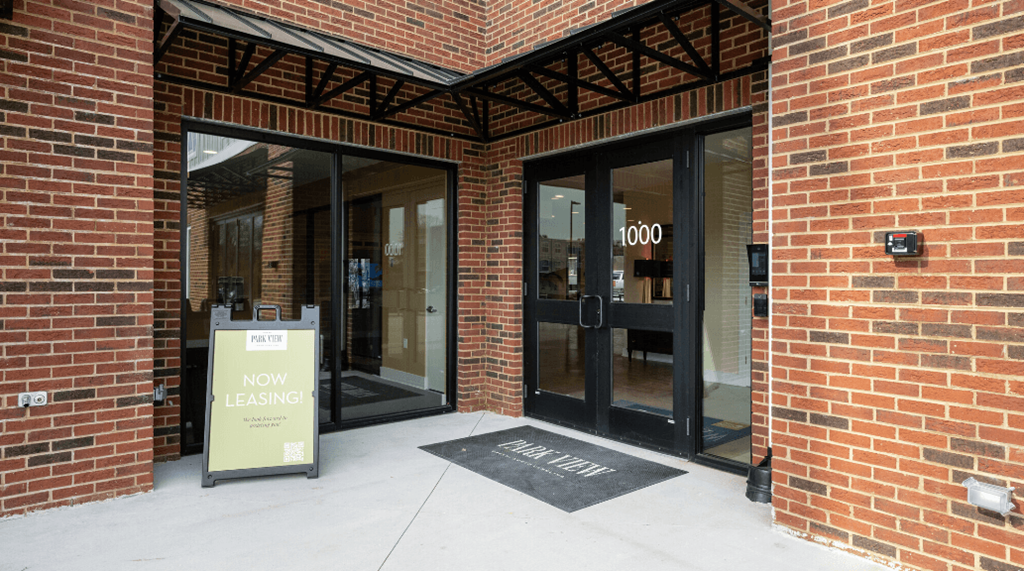 a sign that says now leasing in front of a brick building at Park View Greer, South Carolina